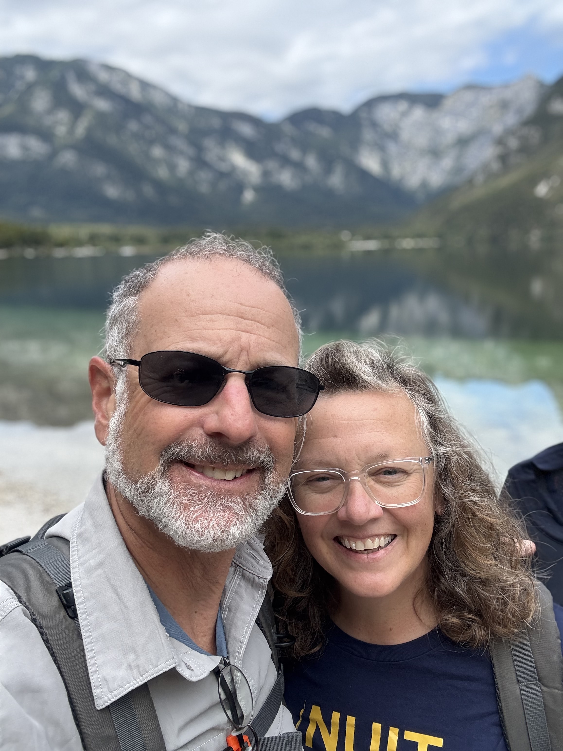 Cheryl and Steve smiling beside a mountain lake
