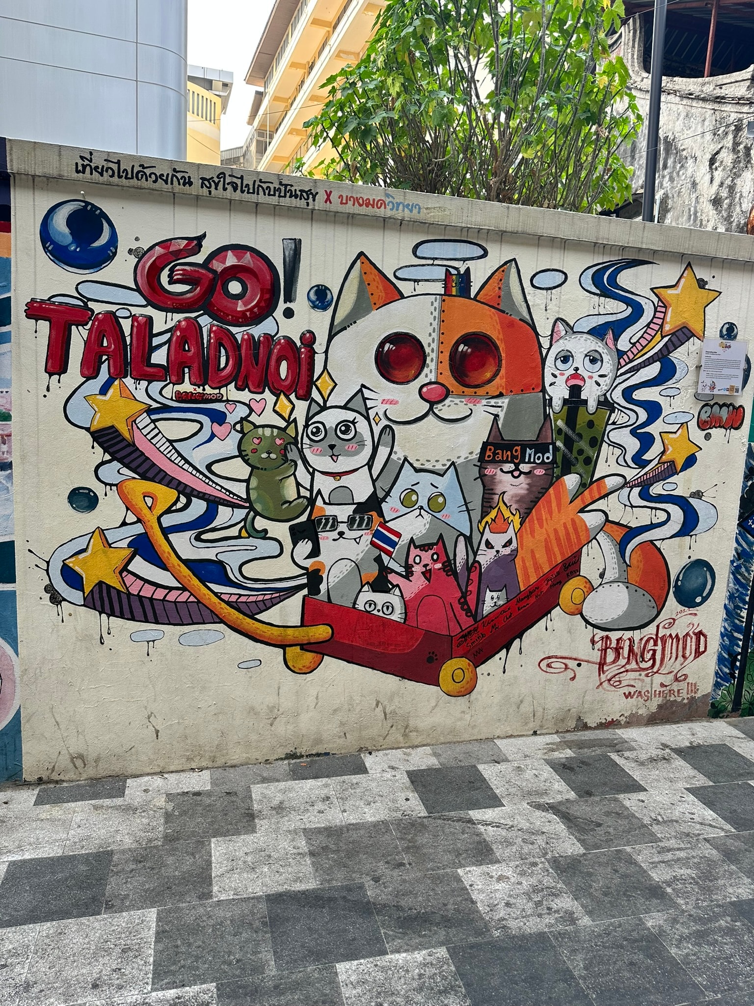Whimsical cat street art mural painted on a building wall in the Talat Noi neighborhood of Bangkok, Thailand