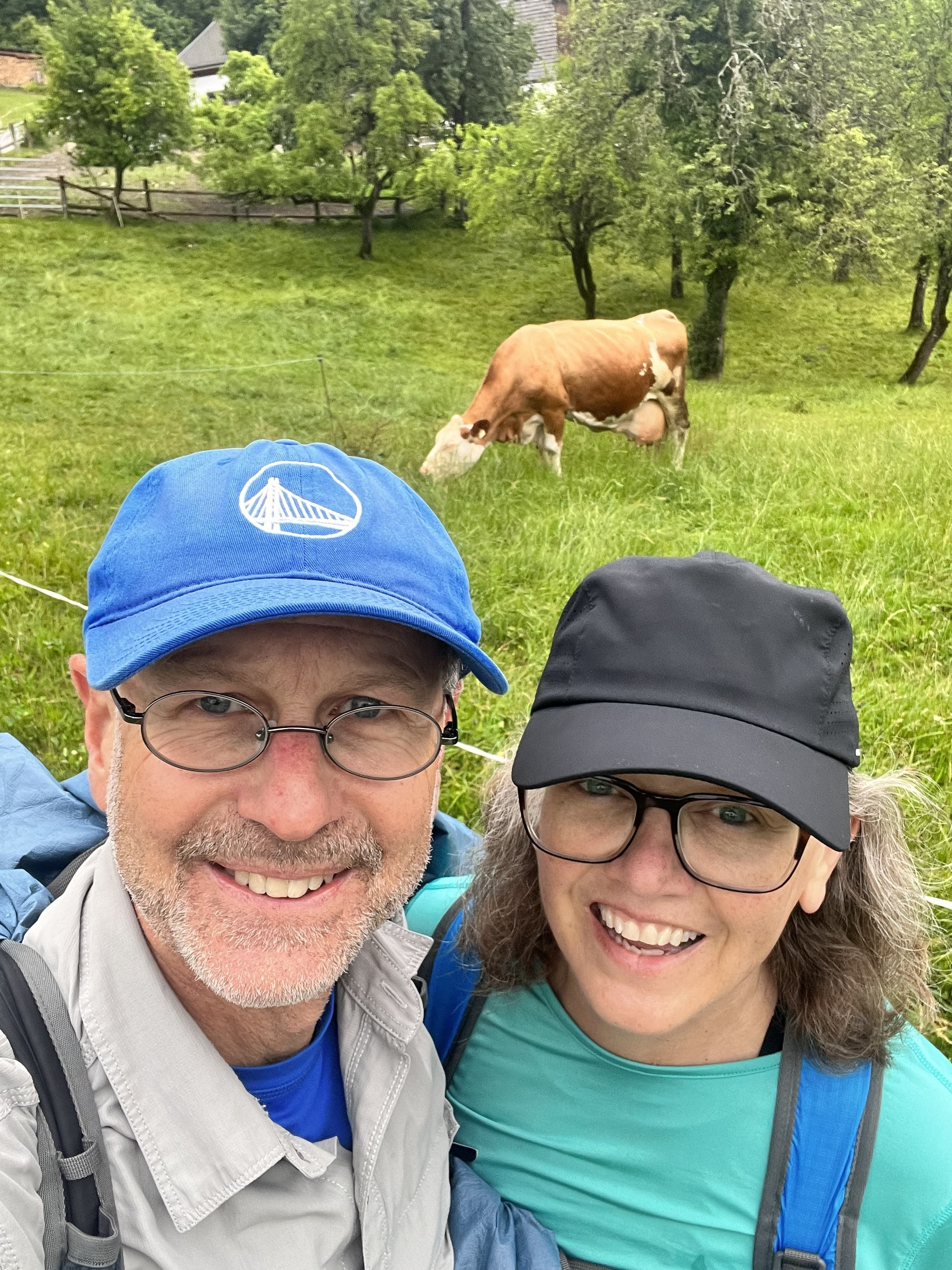 Cheryl and Steve smiling on the trail with a cow in the background