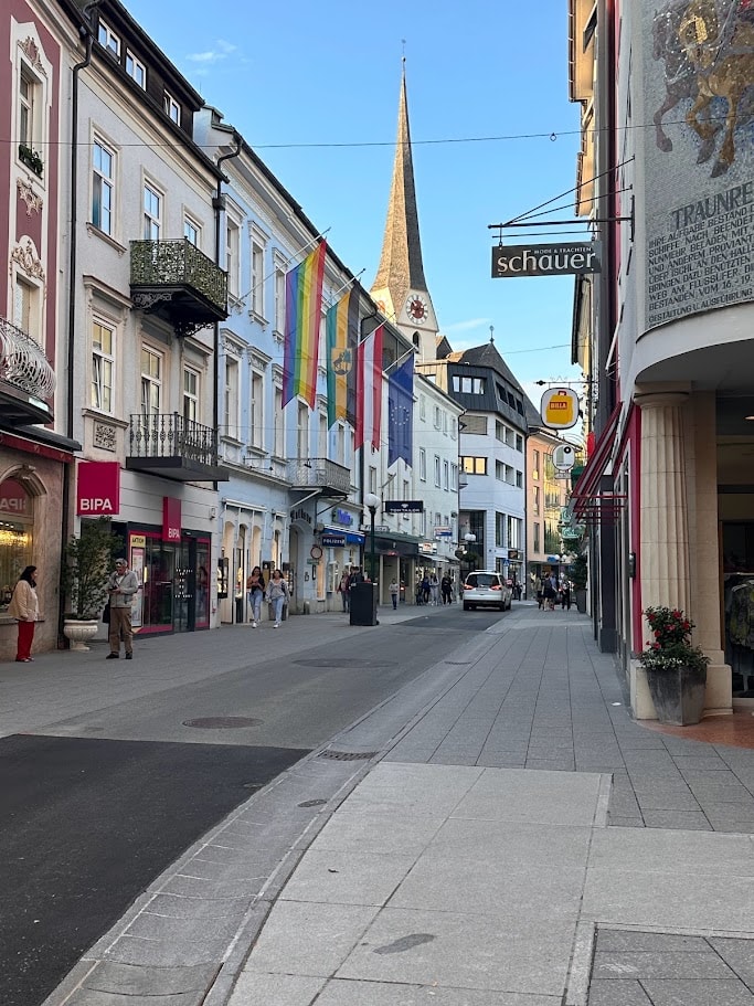 Pedestrian street in the Austrian Lakes region with church spire and colorful buildings