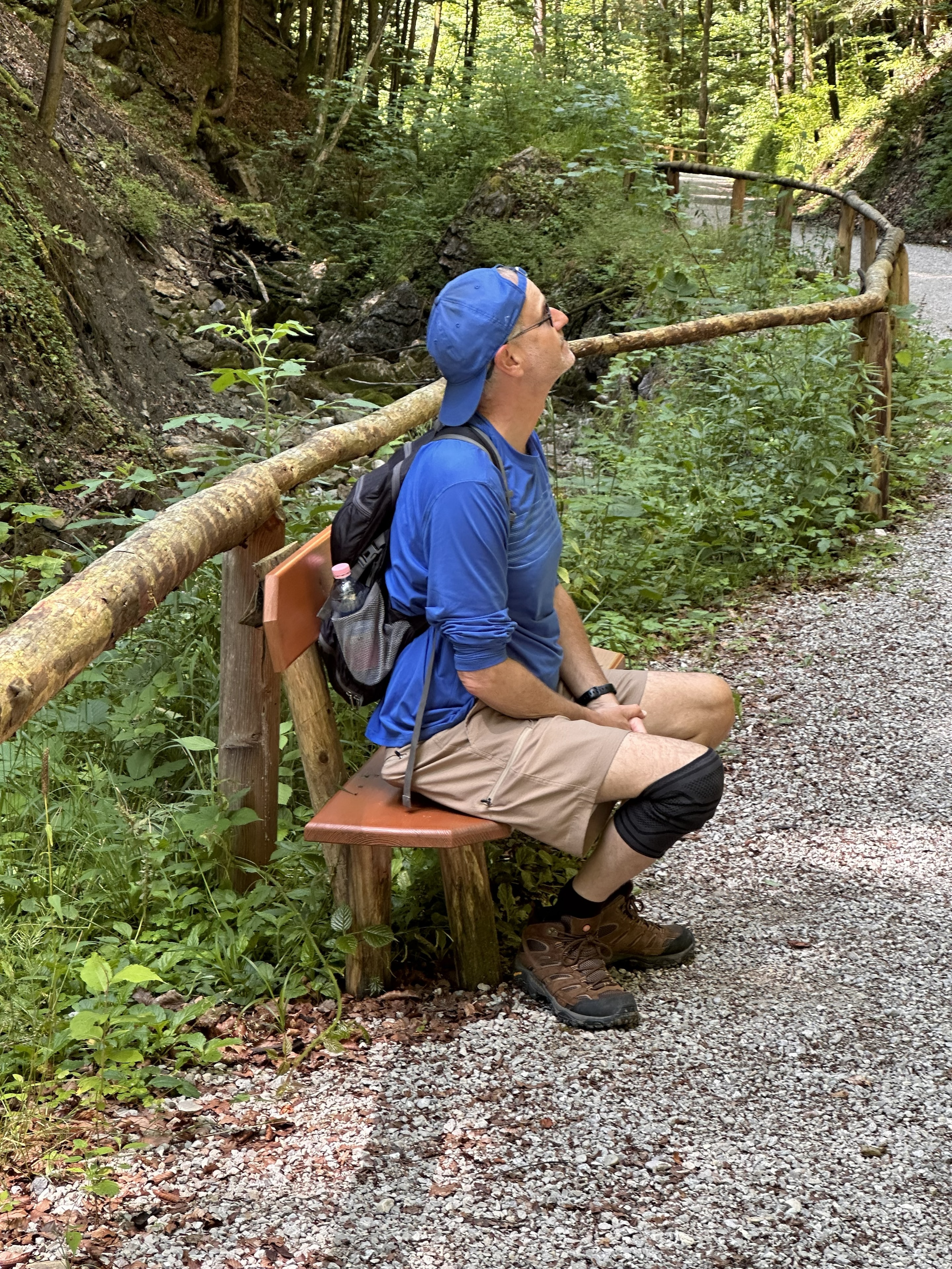 Steve sitting on a trail bench looking up at the mountains