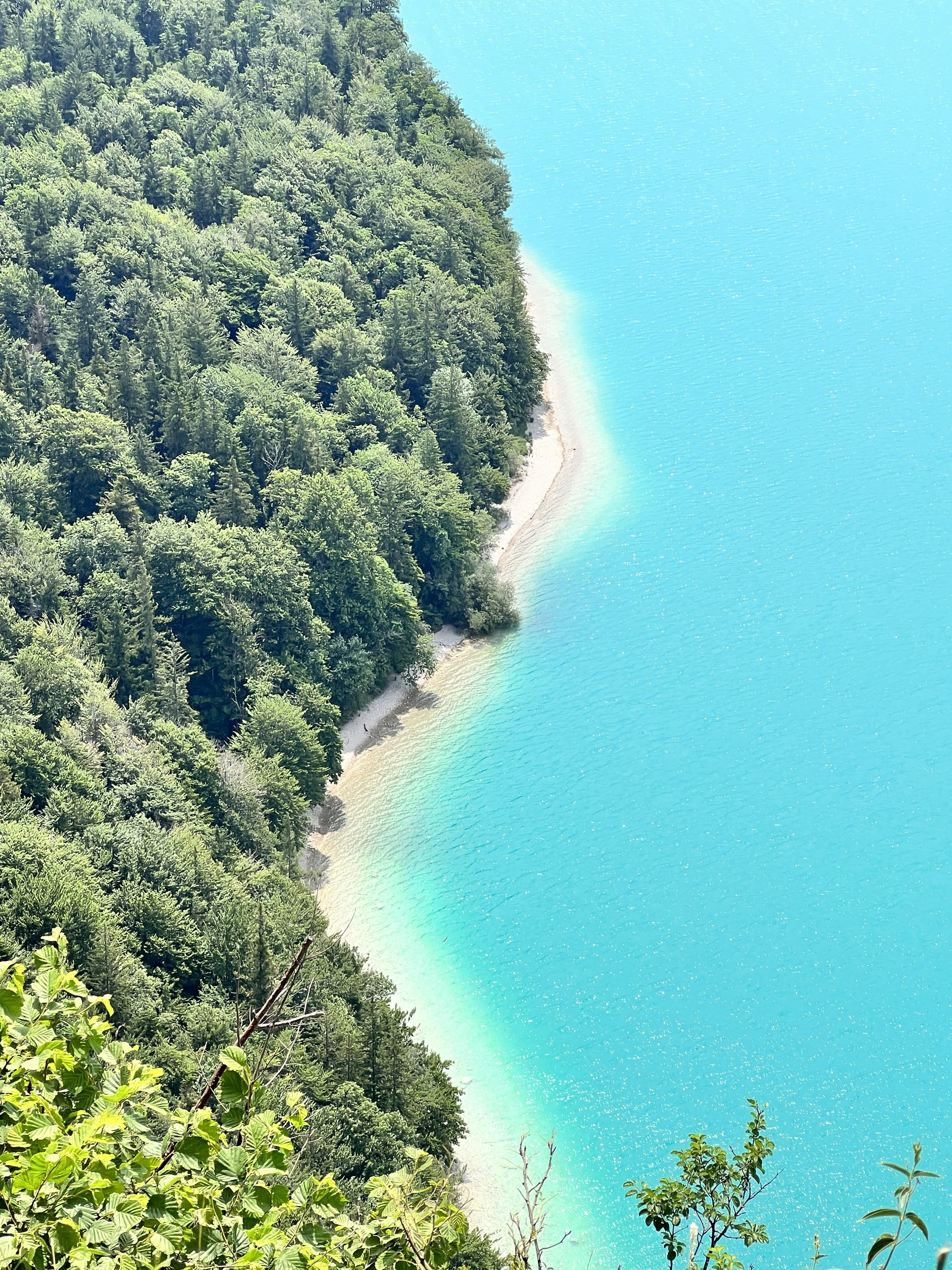 Aerial view of turquoise Wolfgangsee with forested shoreline and sandy beach