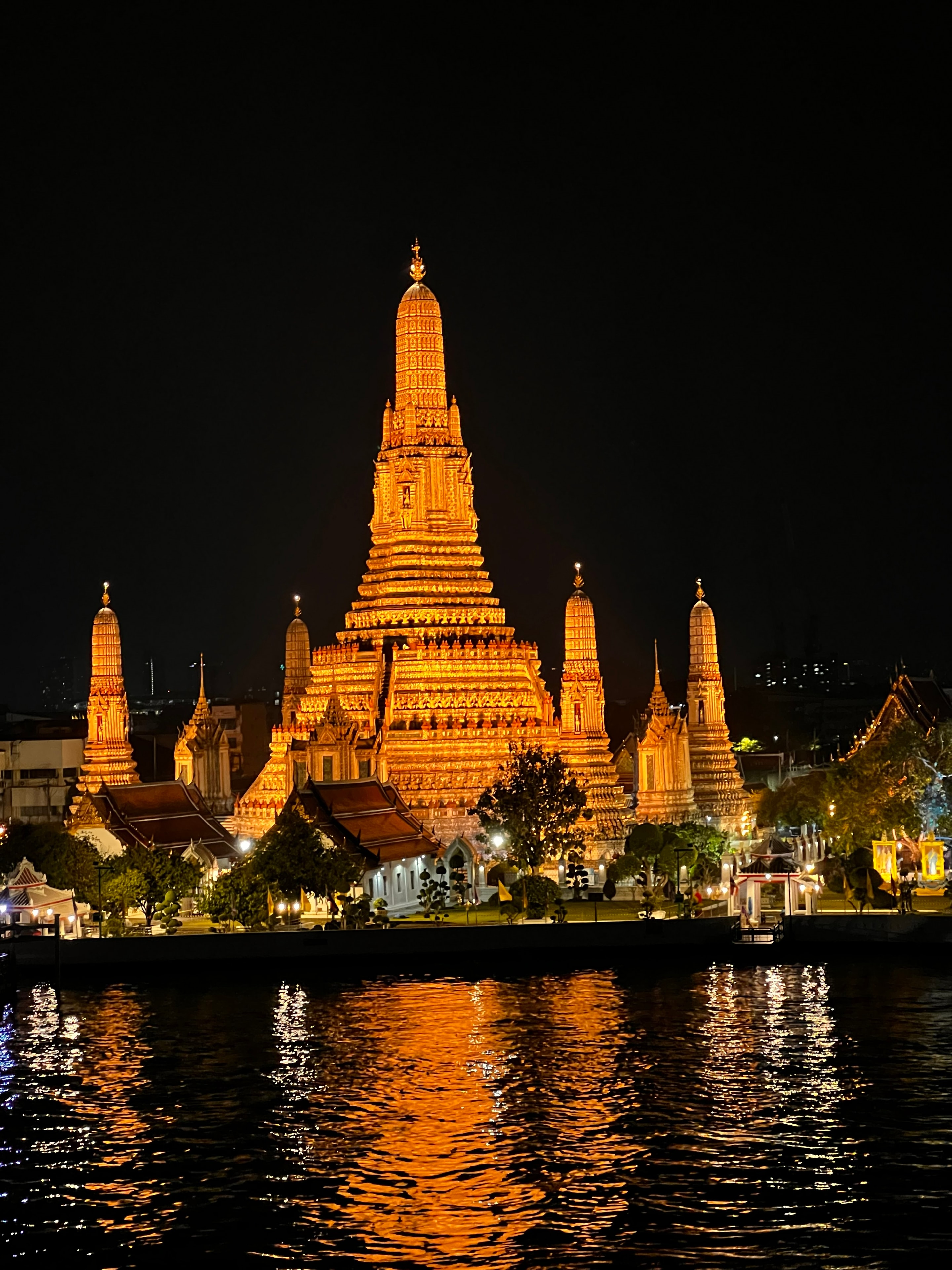 Illuminated Thai temple reflected in the river at night in Bangkok